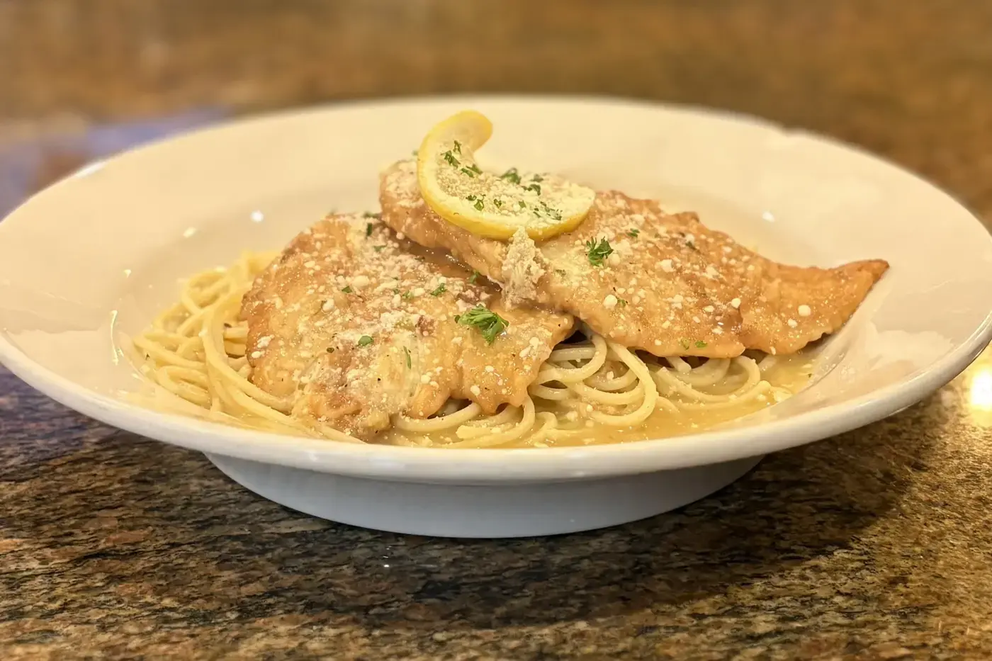 Chicken franchaise over pasta, topped with lemon and parsley