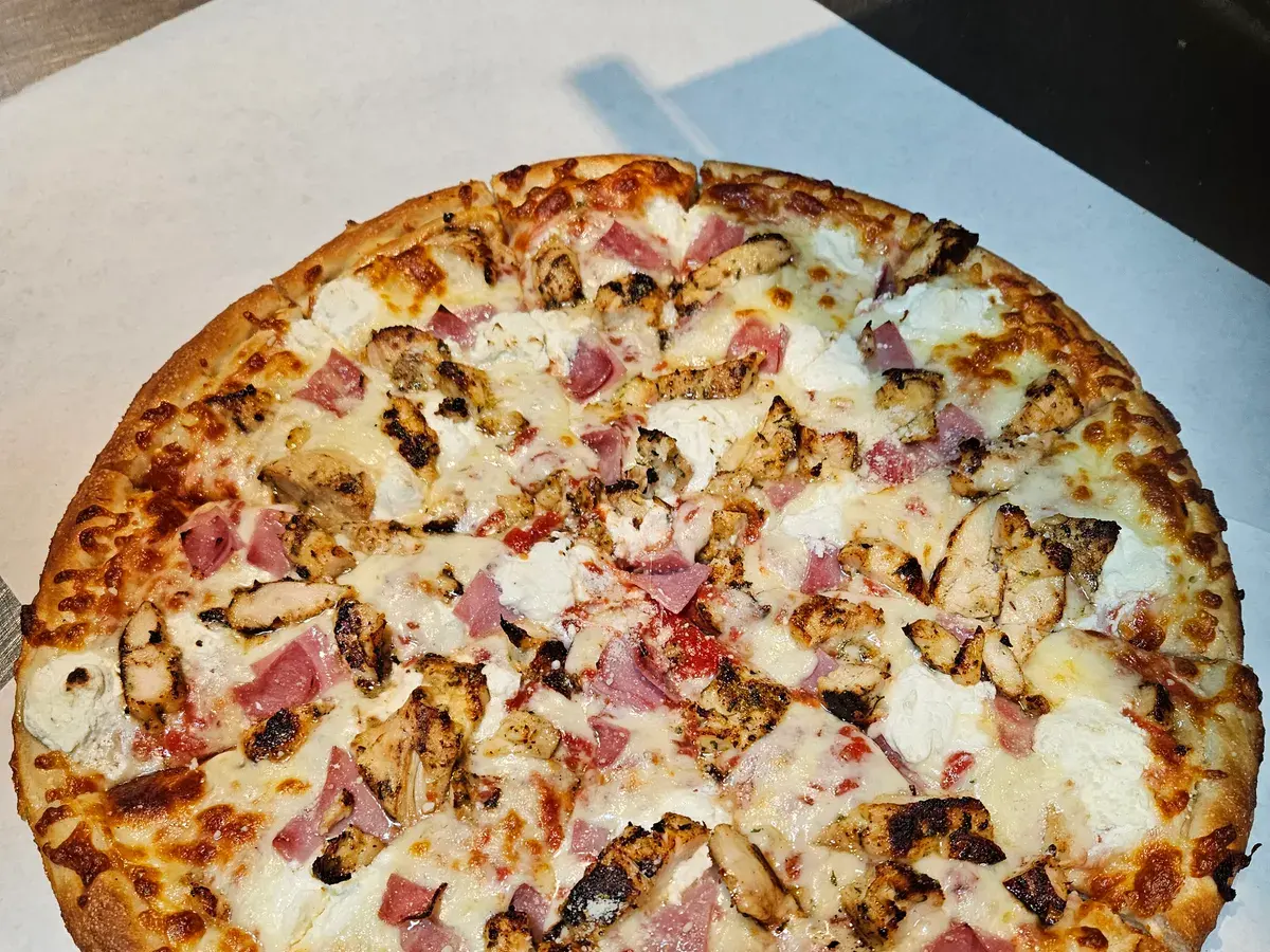 White pizza topped with grilled chicken, ham and ricotta